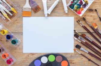 Artist business cards laid out on a desk with paint brushes
