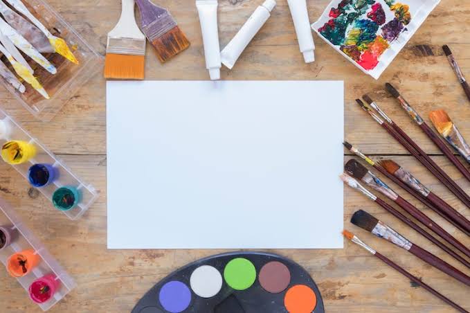 Artist business cards laid out on a desk with paint brushes