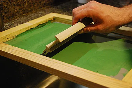 Screen printing at home on a kitchen table with a frame, squeegee and water-based ink