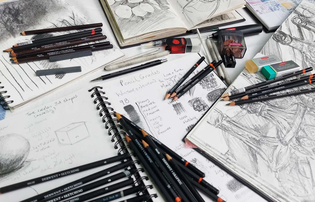 Sketching pencils in a range of graphite grades laid out on a sketchbook